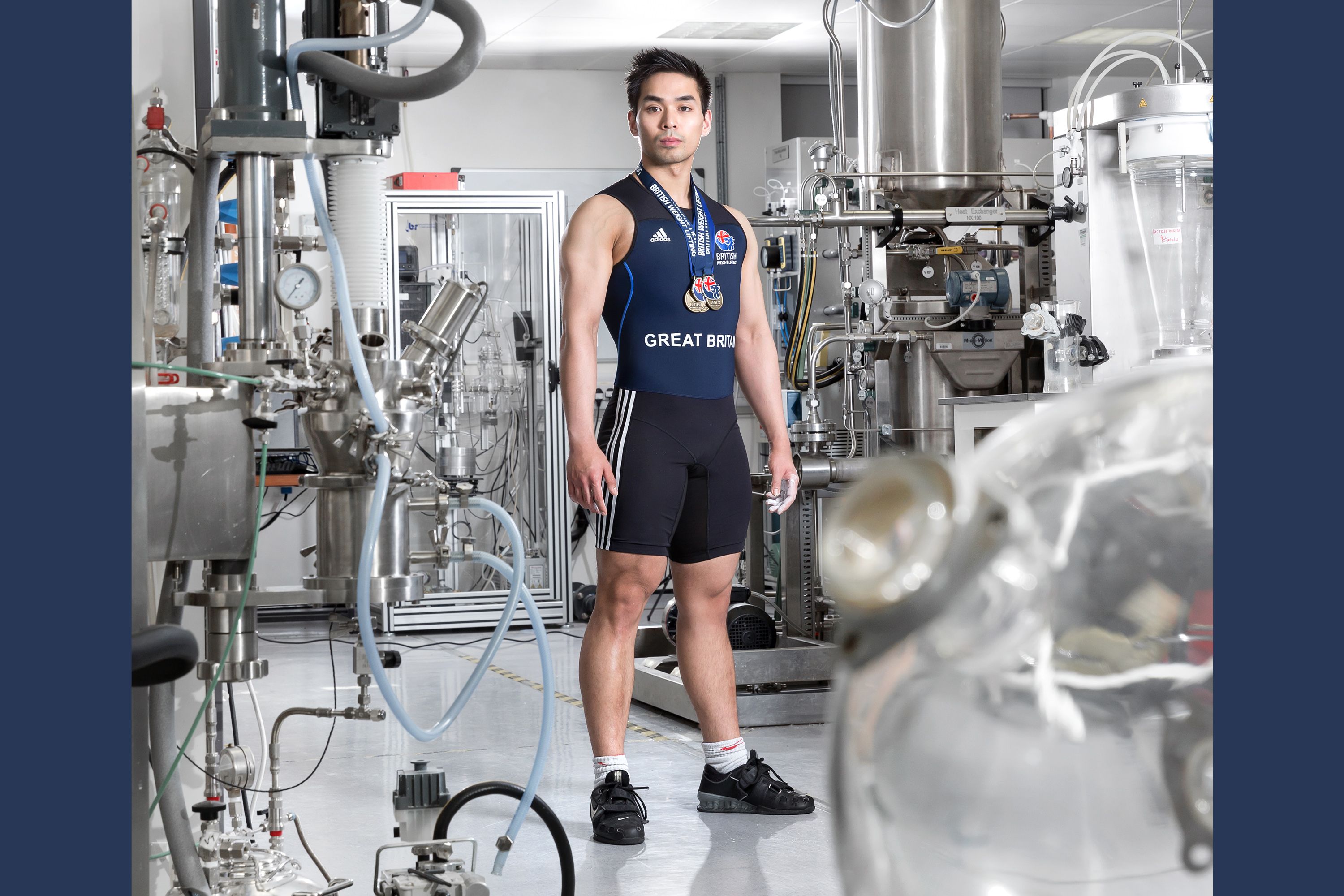 A student in a laboratory wearing Great Britain sports kit with medals around his neck