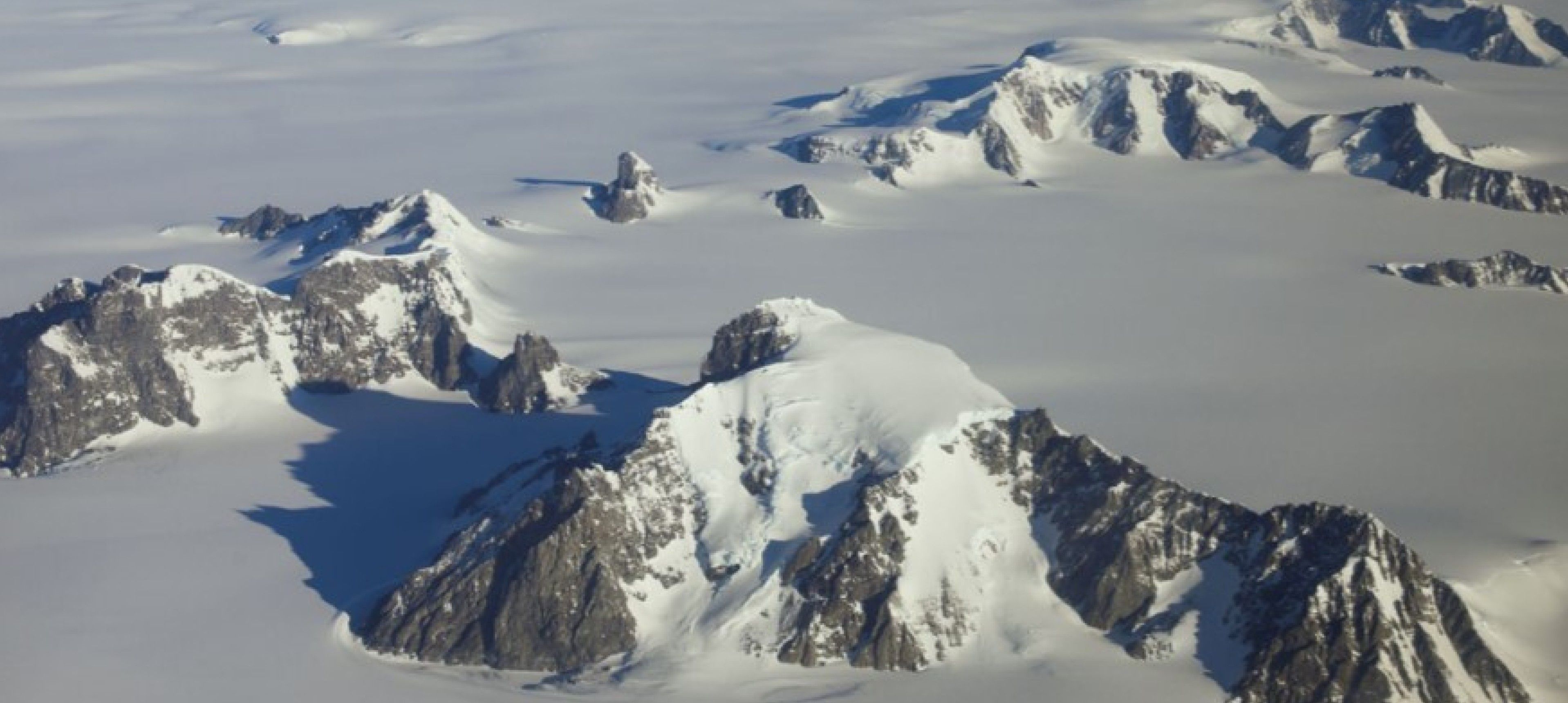 Snow covered landscape with mountains protruding