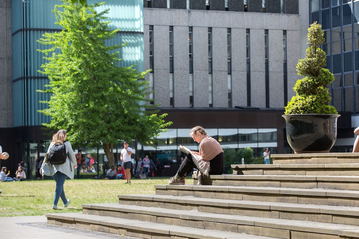 Student sitting on stone steps on the Queen's Lawn