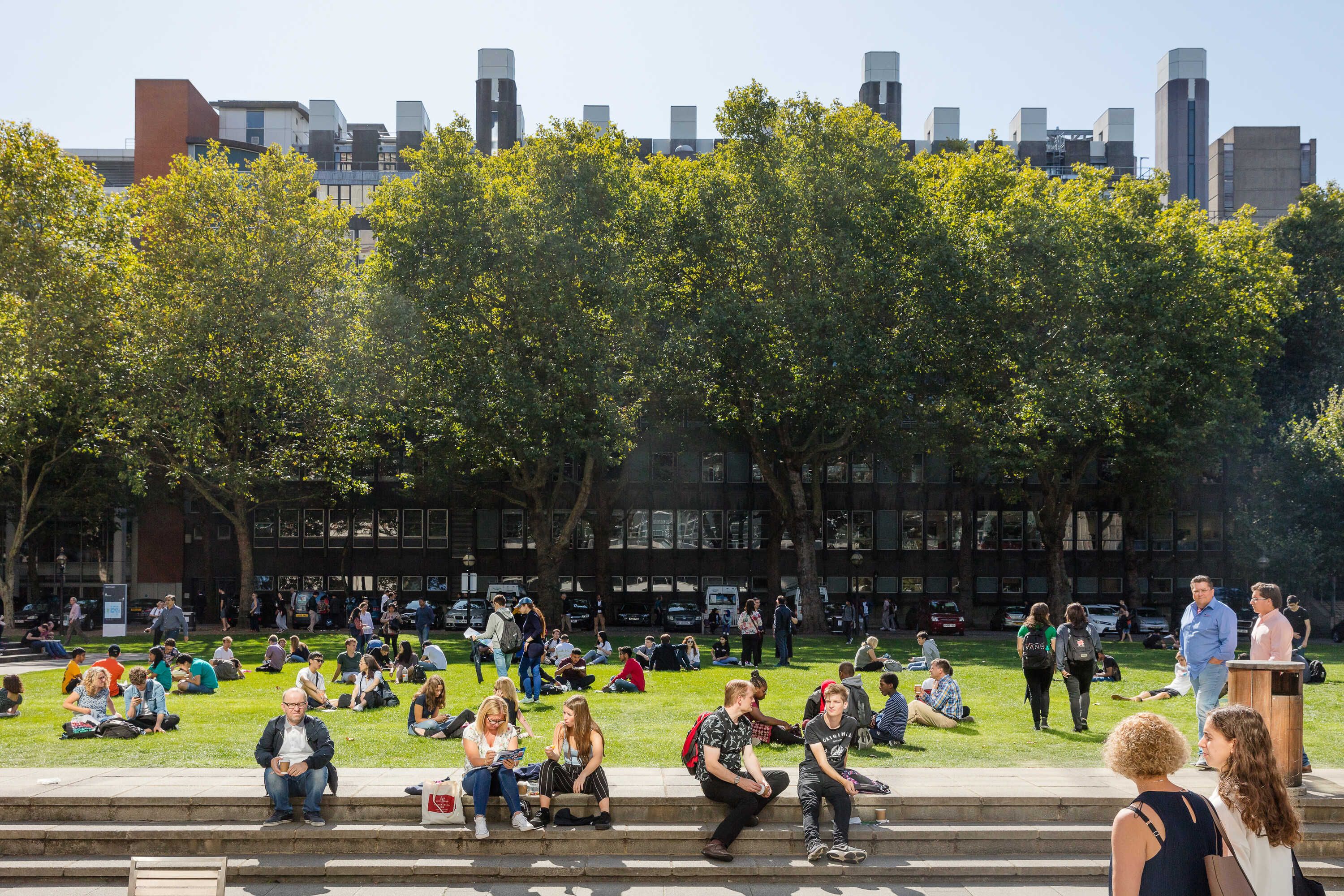 Outside on the South Kensington Dangoor Plaza with people on the grass