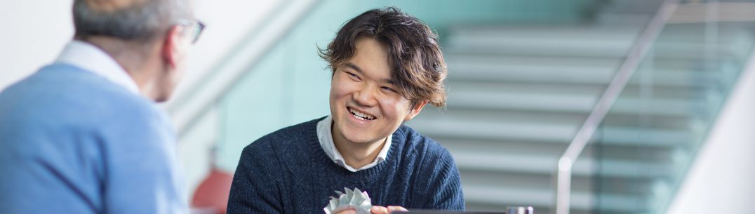 A student smiling holding turbine model talking to staff member.