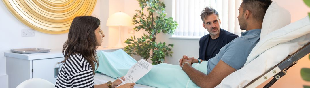 A picture of researchers in and a patient in a research suite