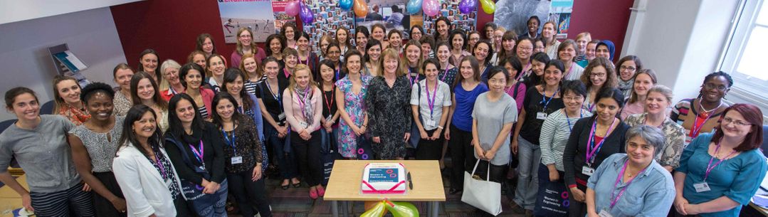 Staff standing around a table with a cake on