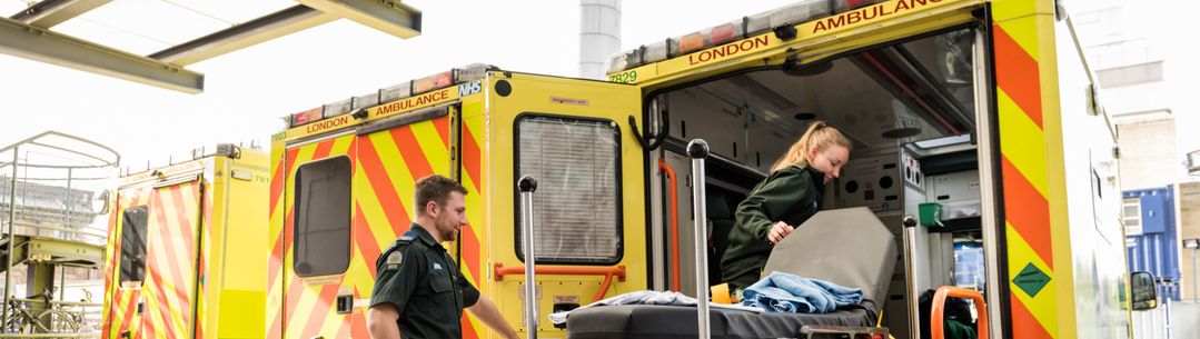 Two paramedics loading a bed on to an ambulance