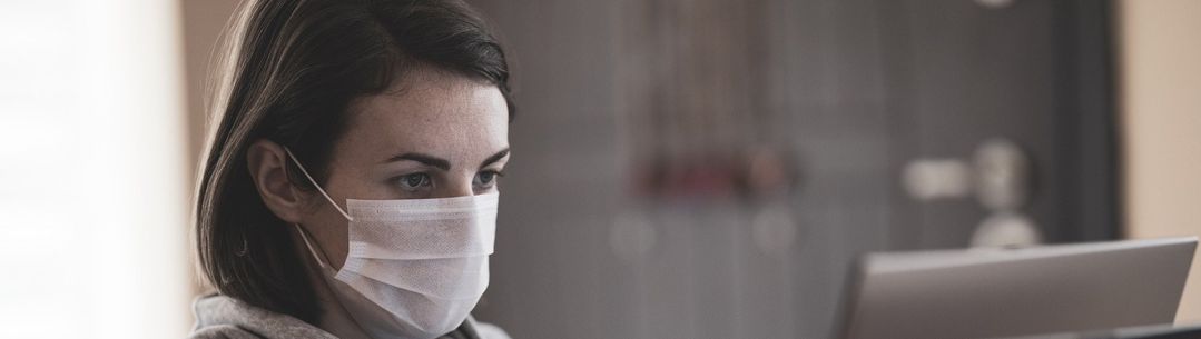 Woman with a mask looking at a laptop