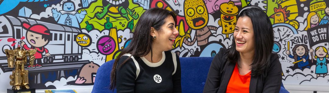 A student and mentor are in discussion while sat on a sofa