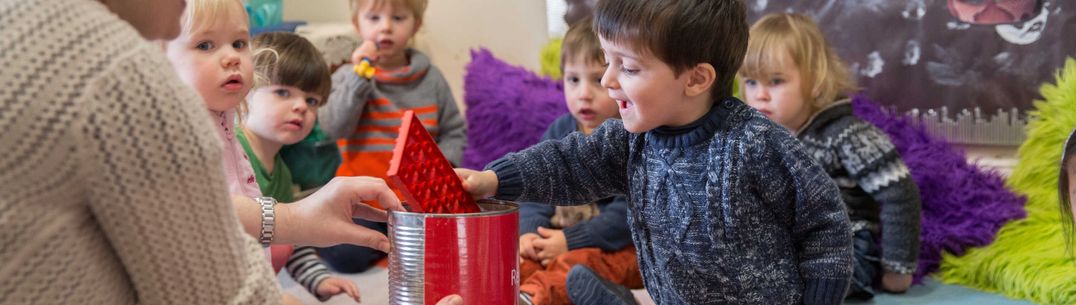 A child inserts a block of Duplo into a box at Early Years