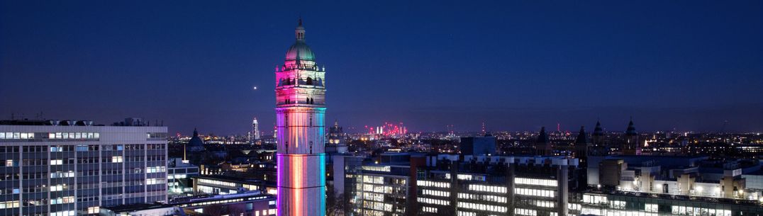 Queen's Tower on South Kensignton campus lit up at night in different colours