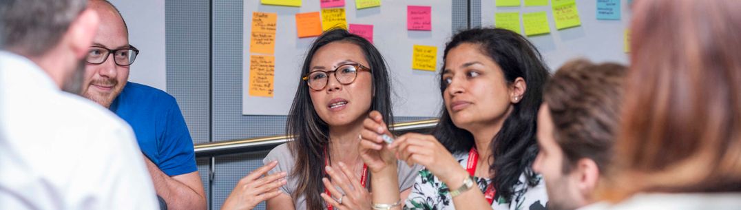 People talking in a creative workshop with colourful post-it notes in the background