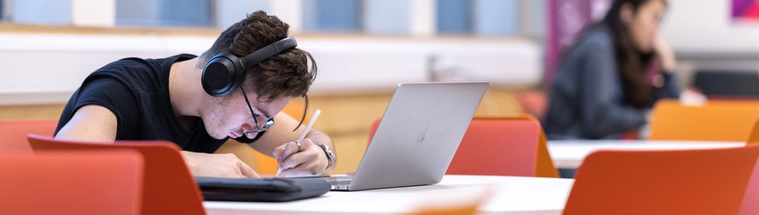 A student listening with headphones whilst studying