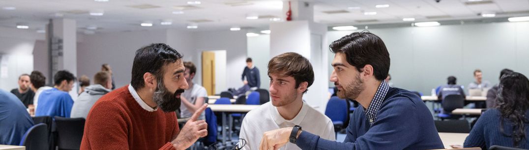 A lecturer and student holding drones have a discussion in a teaching room