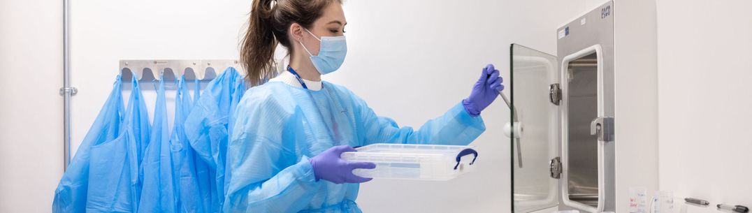 A scientist opens a cabinet door to place in a tray of samples in the new testing lab for COVID-19