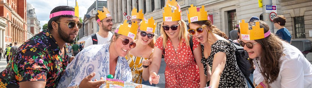 A group of Great Exhibition Road Festival attendees wearing festival hats and reading a festival map
