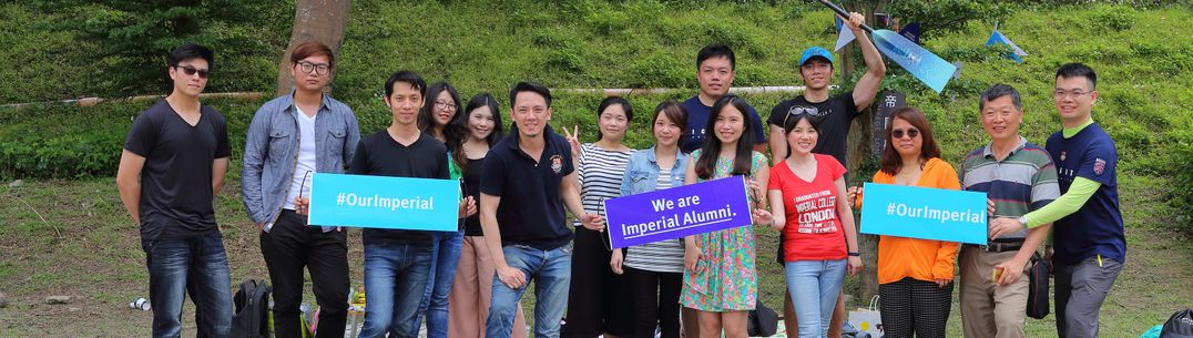 Group of alumni holding Imperial banners smile at the camera in Taipei