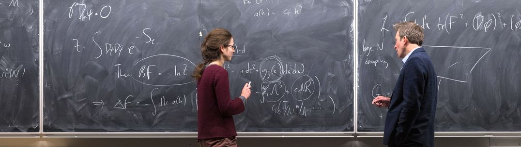 A professor and PhD student work on a blackboard with equations about quantum theory of spacetime