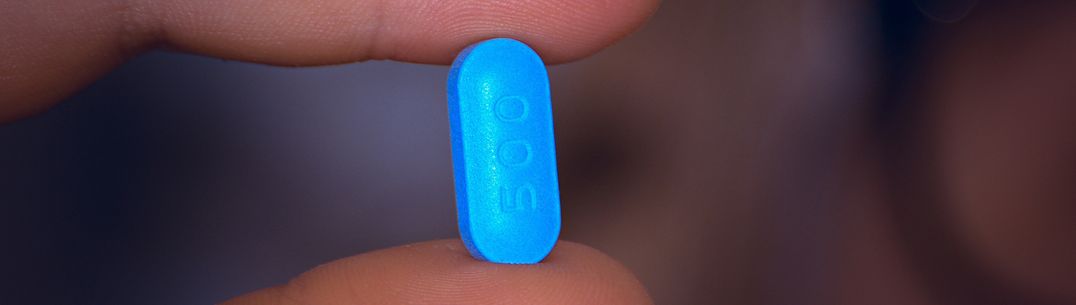 A picture of a blue pill being held between two fingers. Image by Tomasz Ryś from Pixabay