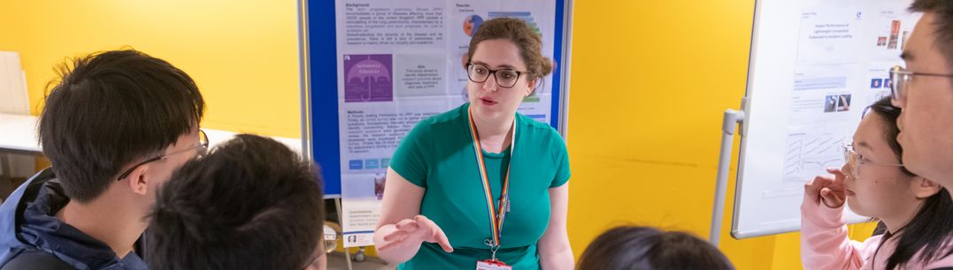 A speaker presenting to a group of students at a poster event