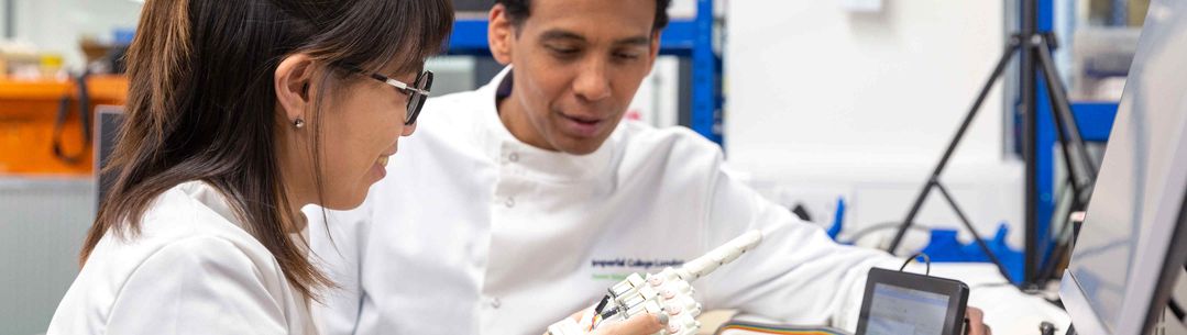 Design engineering student and researcher looking at a robotic hand