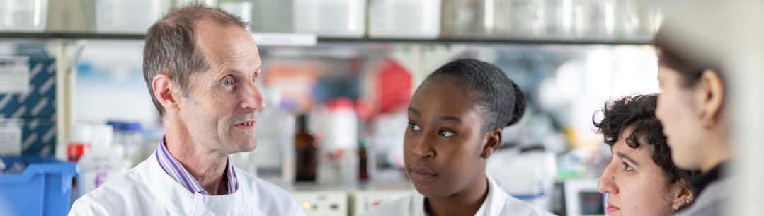 Professor Robin Shattock talking to members of the vaccine research team in the lab