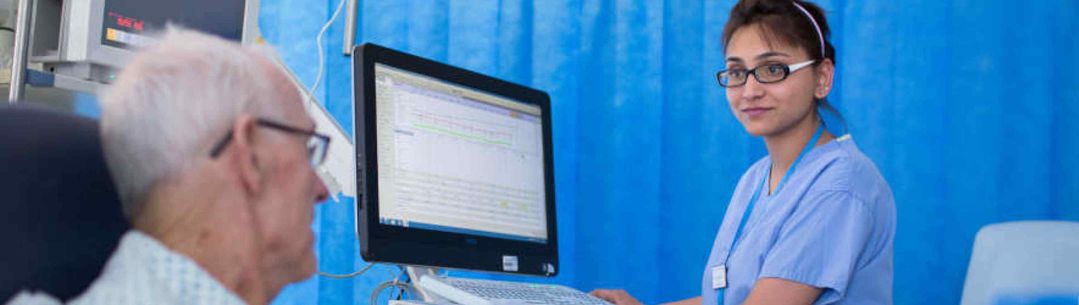 A nurse talking with an elderly patient in a hospital bed