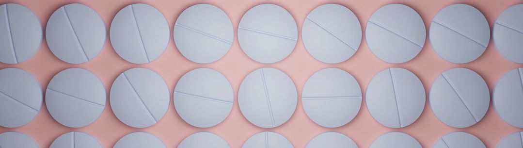 White pills on a pink background
