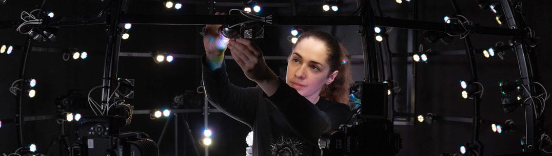 Female PhD student adjusting the Multispectral Light Stage, a sphere of white lights