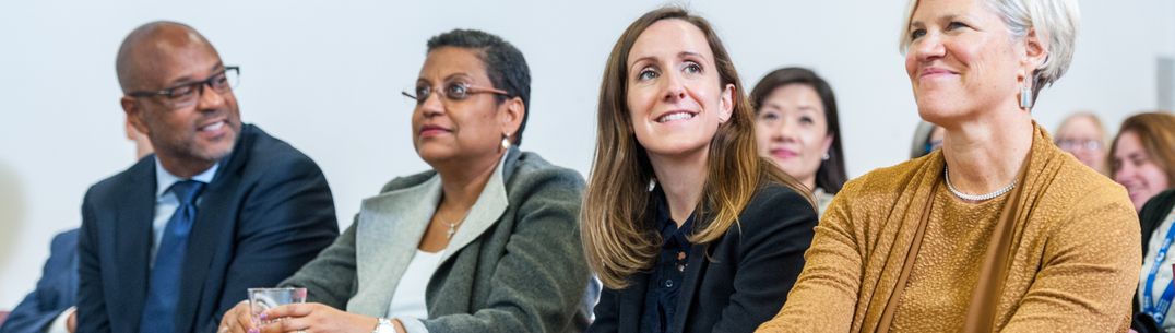 four members of staff sat in a row listening to a talk