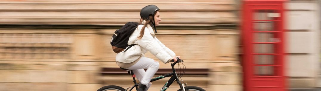 A female student cycles on her bike down Exhibition Road