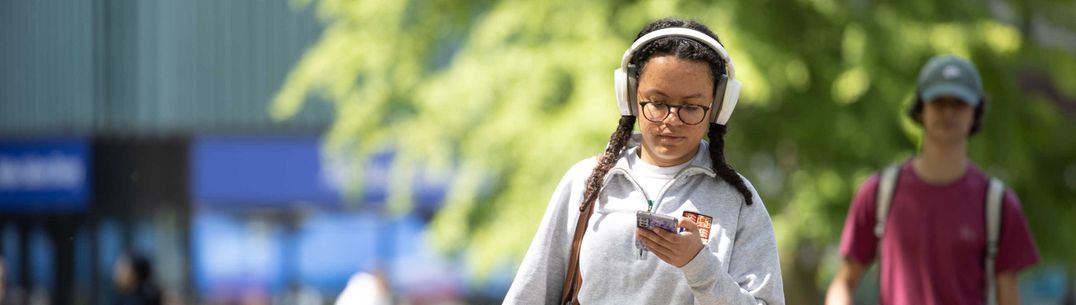 Student walking on campus with phone in hand