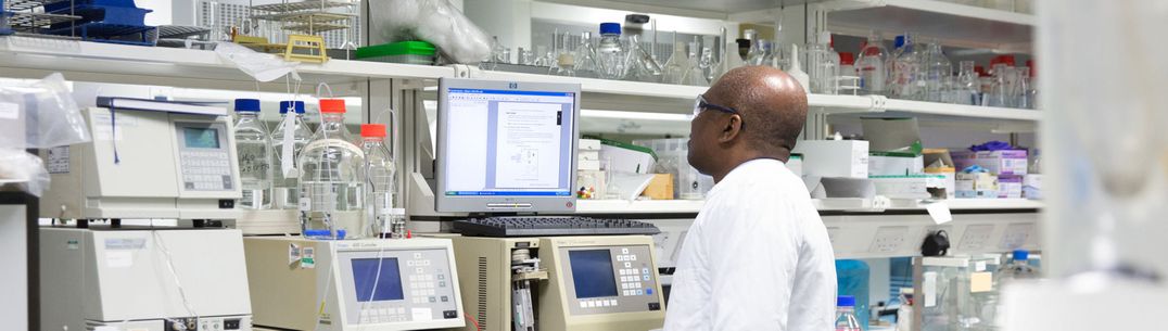 A researcher in a lab coat looks at a computer screen during an experiment