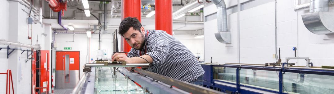 A researcher sets up a rig above a water tank in the fluid mechanics laboratories