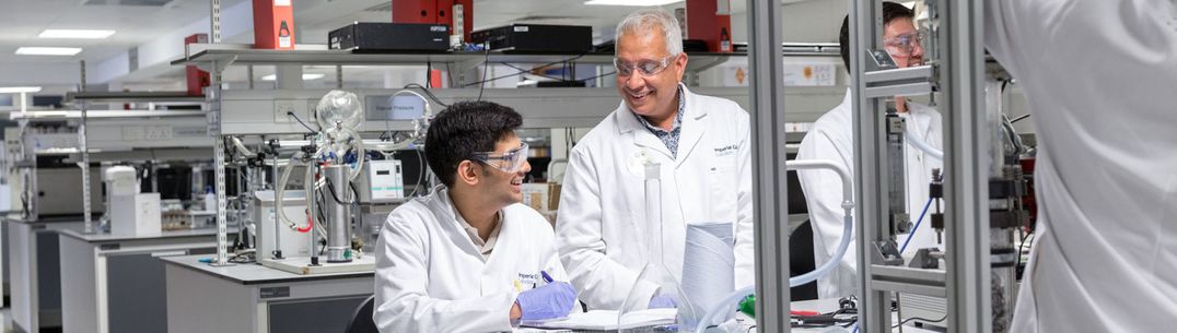 A student working at a lab bench talks to a member of staff