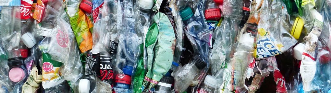 A bale of plastic bottles of all colours, flattened together and ready for recycling