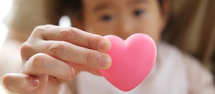 Baby and mother holding heart symbol