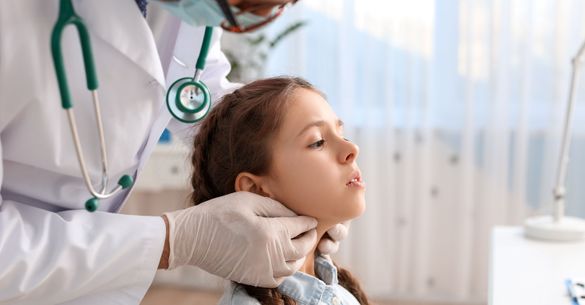 Doctor examining little girl's neck in clinic