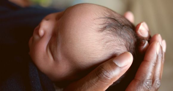 Daddy holding newborn baby's head in his hands