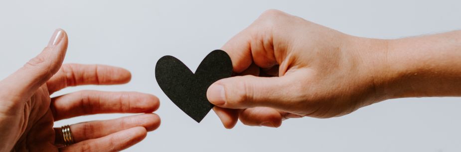 hand giving paper heart to someone