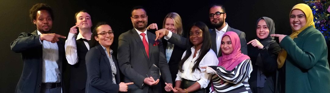 Harris Bokhari and his guests on stage pointing to his award