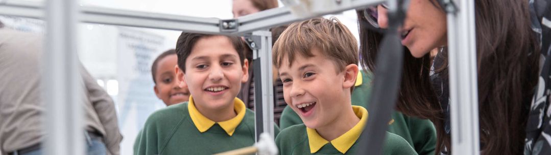 Primary school children smiling as they watch an experiment.