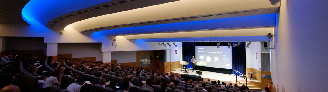 An auditorium full of people watching a lecture take place.