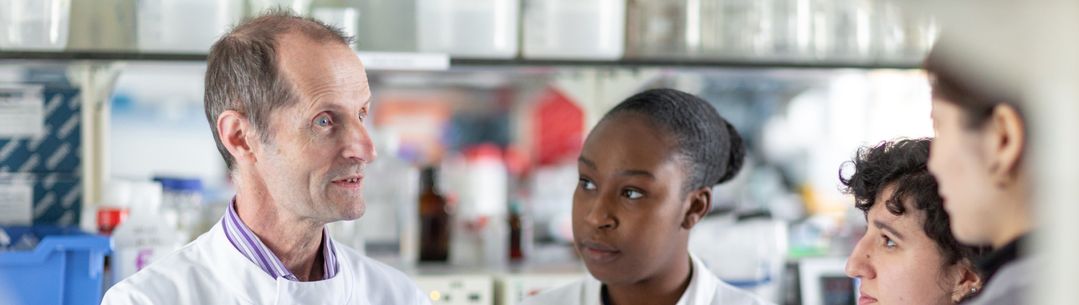 Professor Robin Shattock talking to members of the vaccine research team in the lab