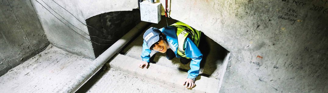 A woman emerges from a tunnel wearing a hat with text RatSoc