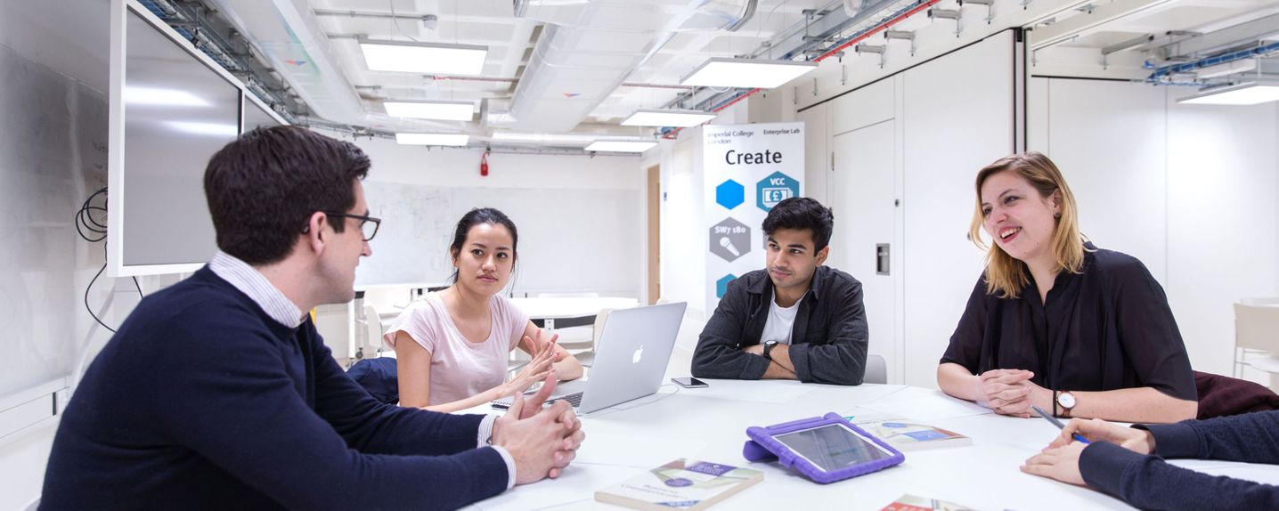 A group of students and a lecturer working on a robotic arm during a class