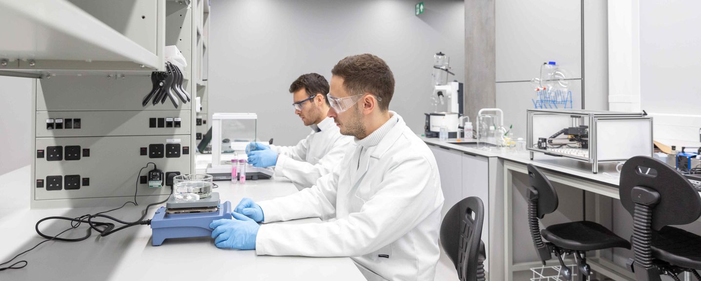 Two researchers sat at a lab bench handling equipment