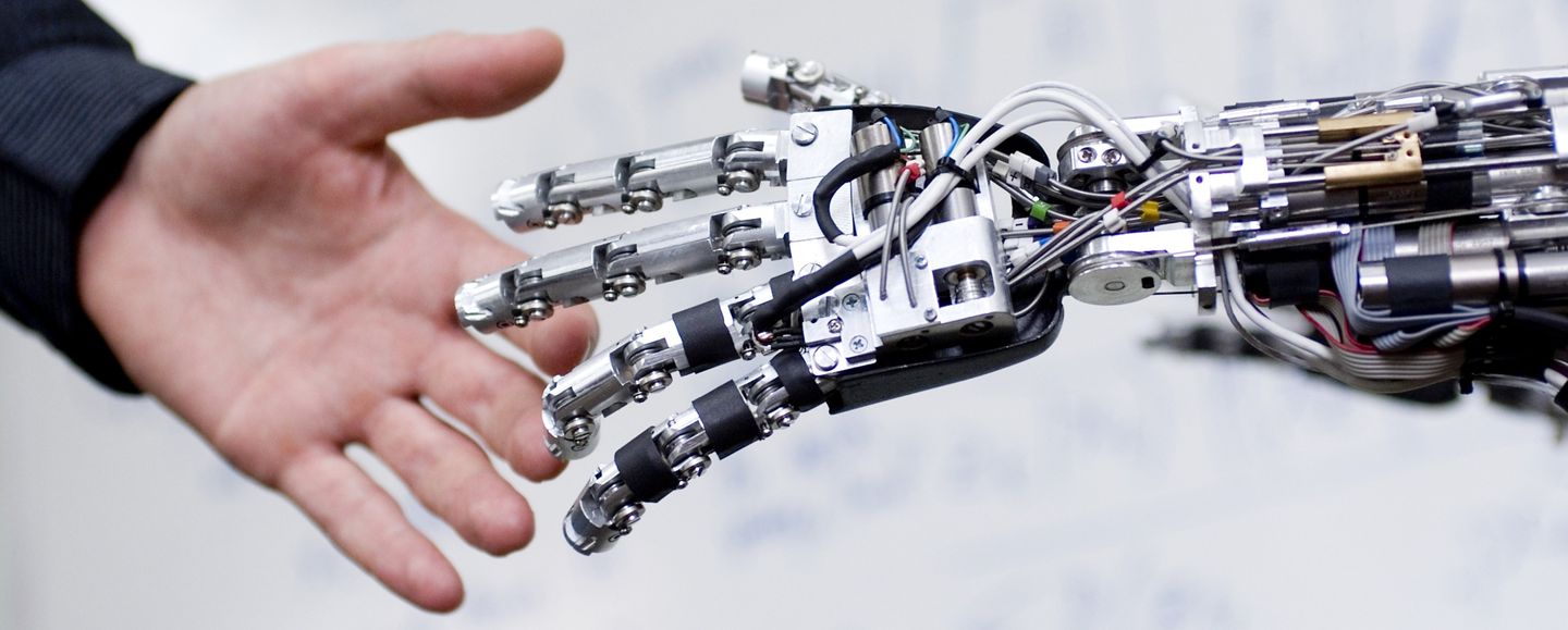 A human hand reaching out and touching a silver robotic hand