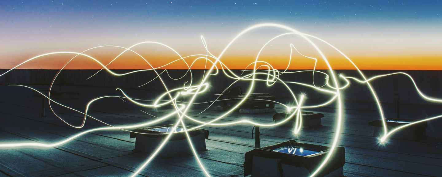 Bright wavy lines travelling over a roof top at dusk