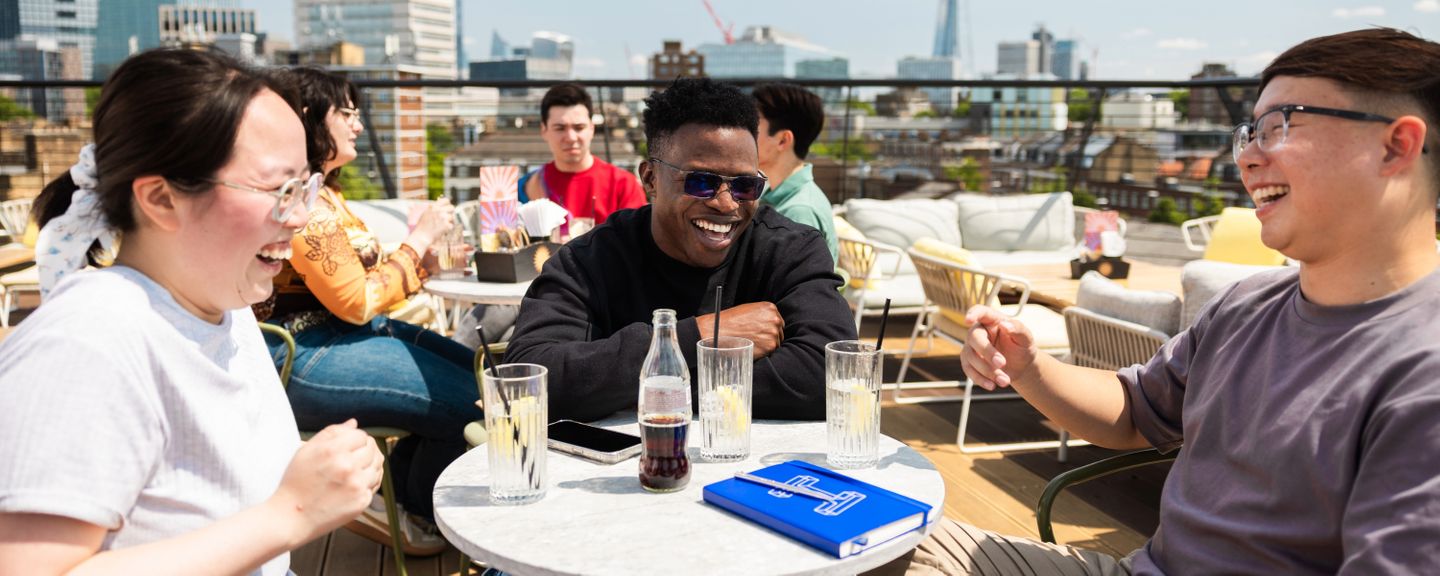 Students sitting in the sunshine on a rooftop bar in London