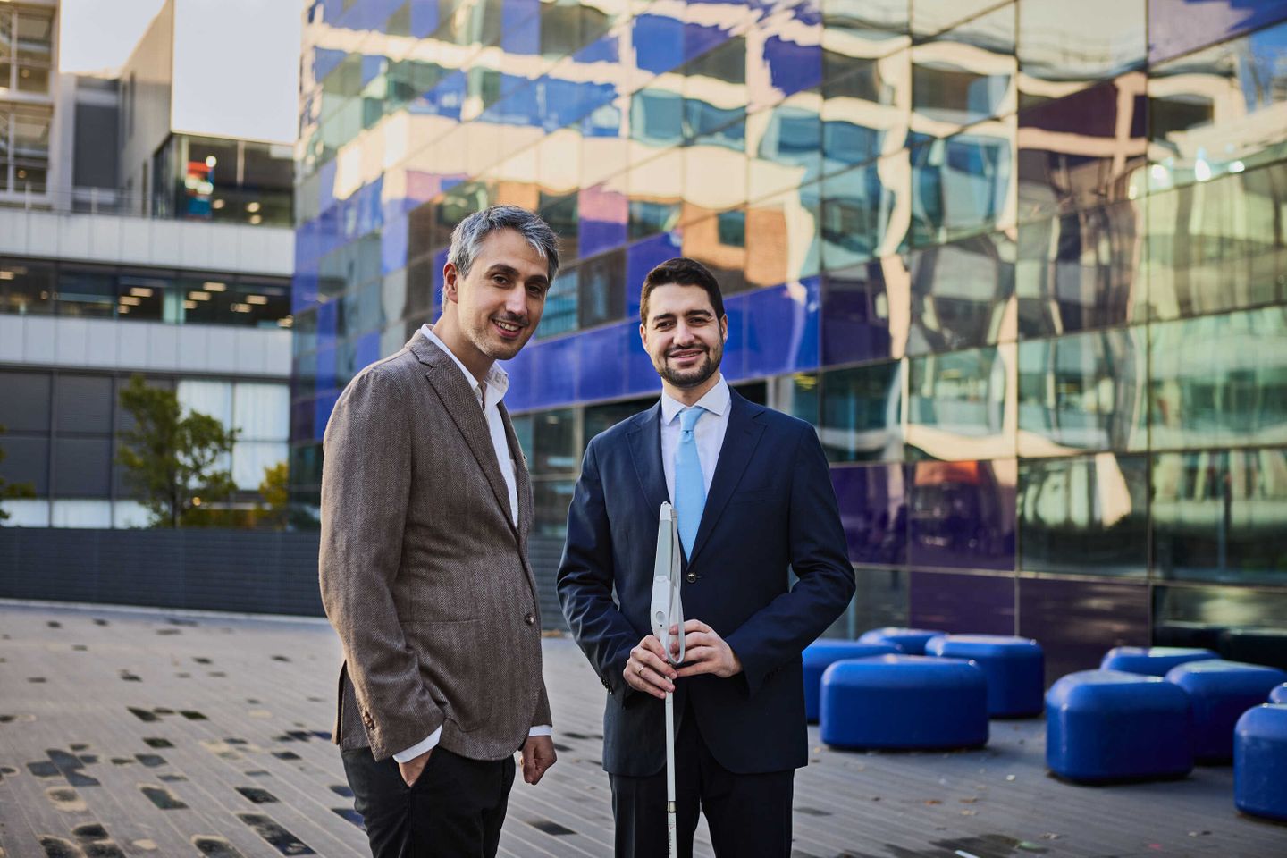 Two men stand outside the Faculty building