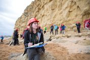 An earth science student writing in a notebook on a field trip to the coast