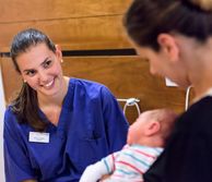 A nurse smiling at a new mother and her baby